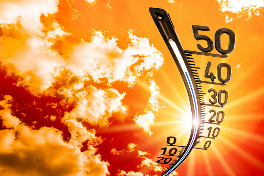 Ein Thermometer steigt vor einem orangenen Himmel mit Wolken in der Hitze auf über 40° Celsius