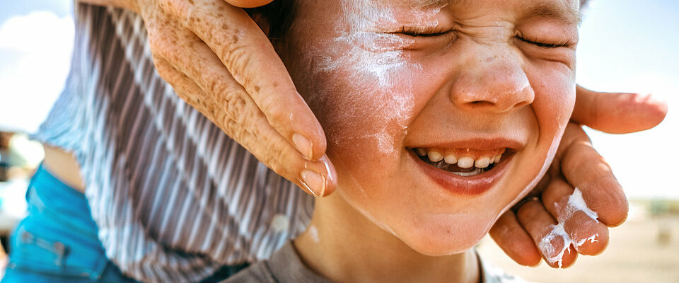 Ein Kindergesicht wird angesichts der Hitze mit Sonnencreme behandelt