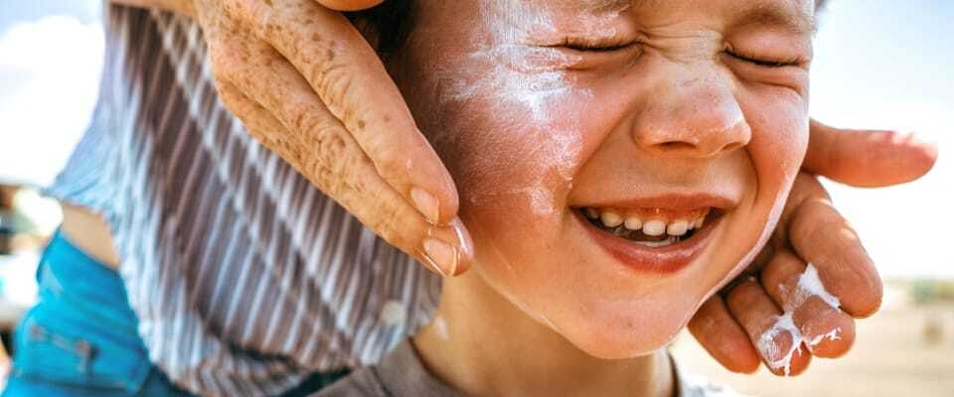 Gesicht eines Kindes, auf das Sonnencreme aufgetragen wird