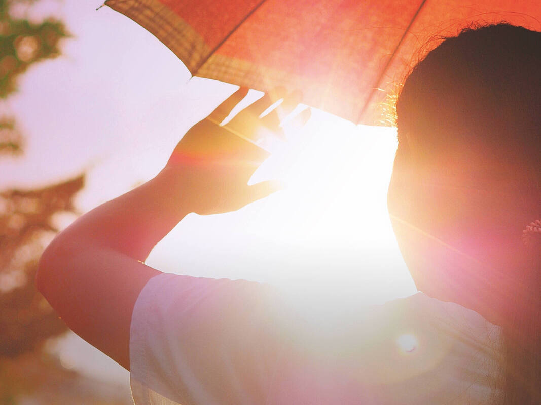 Eine Person streckt die Hand vor ihr Gesicht und hält einen Sonnenschirm, um die Sonnenstrahlen abzuschirmen.