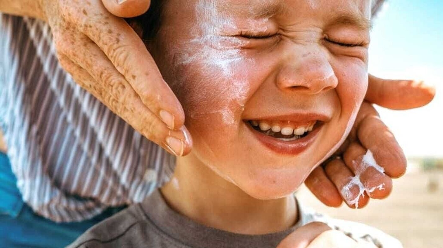 Gesicht eines Kindes, auf das Sonnencreme aufgetragen wird