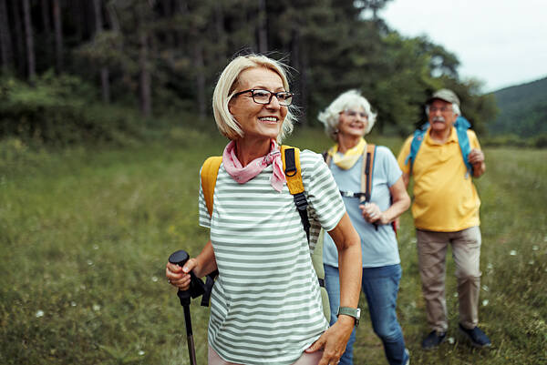 Zwei Seniorinnen und ein Senior draußen beim Wandern
