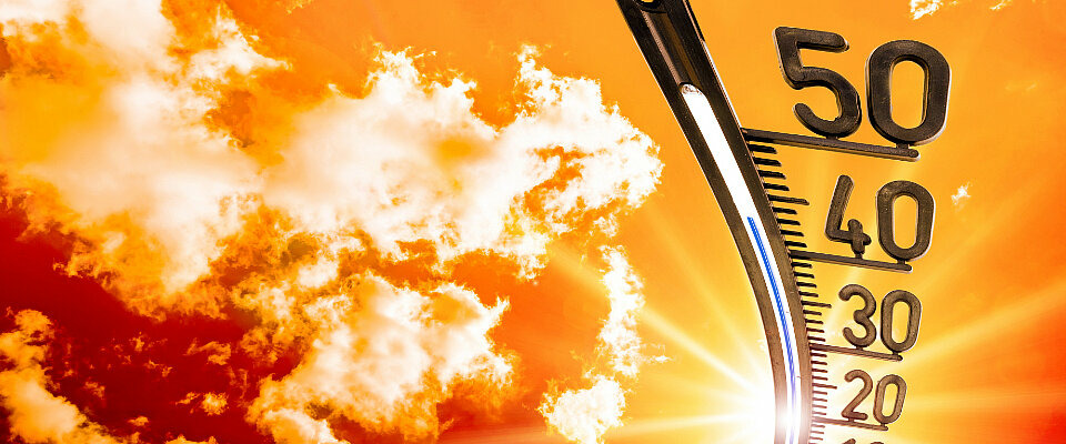 Ein Thermometer steigt vor einem orangenen Himmel mit Wolken in der Hitze auf über 40 Grad Celsius