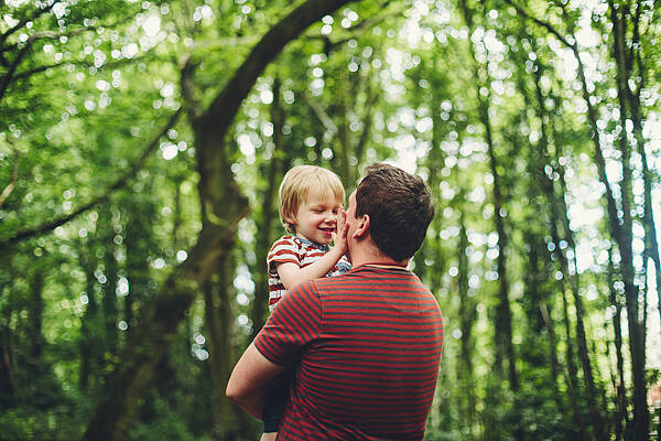 Vater mit Kind auf dem Arm im Wald